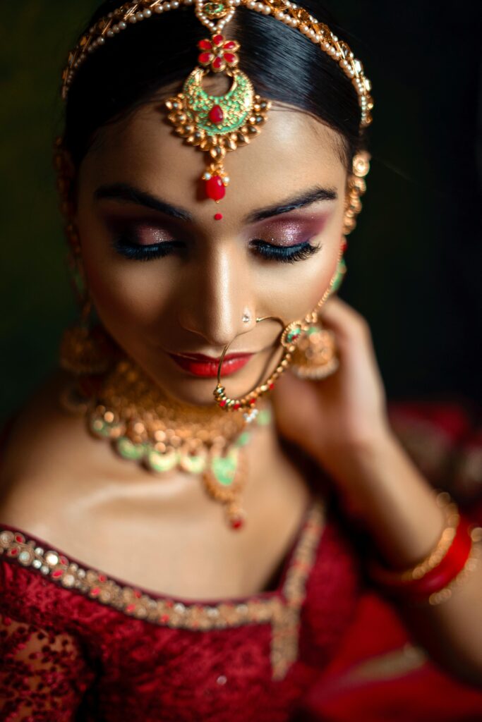 HD vs. Airbrush Makeup: Which One Is Better for You? Close-up portrait of an Indian bride in traditional red sari and jewelry.